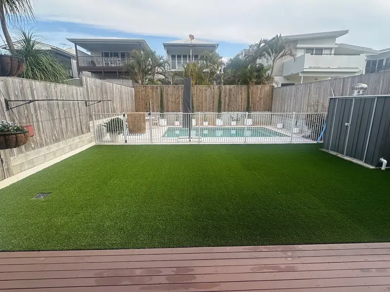 Artificial grass backyard beside a fenced pool