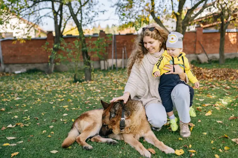 A mum and her child sitting with their dog on a lawn (stock photo)