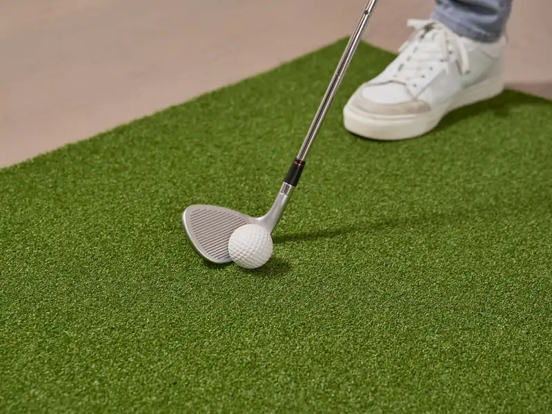 A golf club and ball on short putting turf (stock photo)